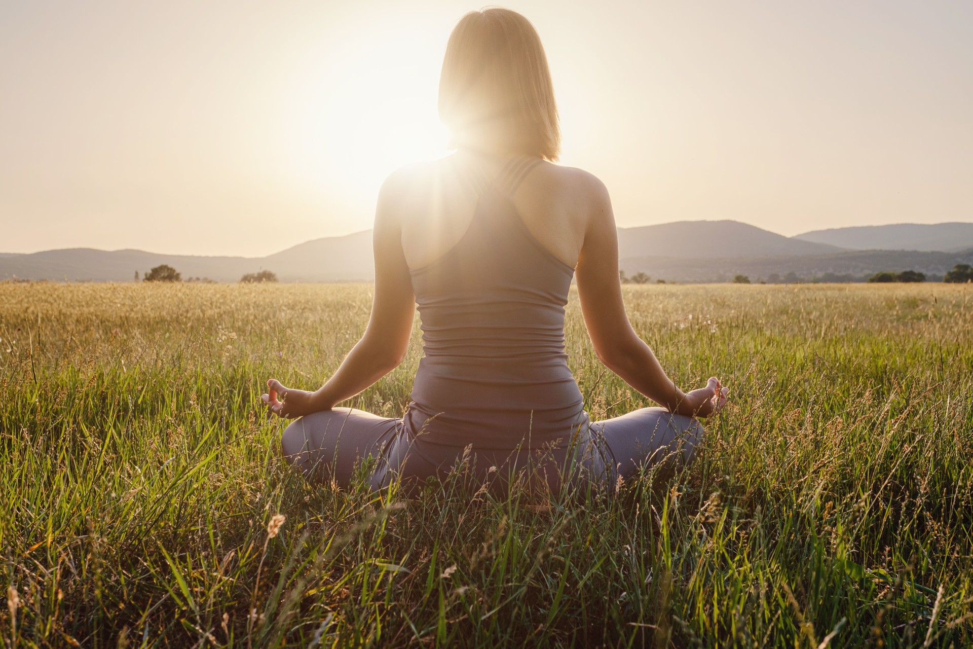 woman practices yoga and meditates in the lotus position on the field